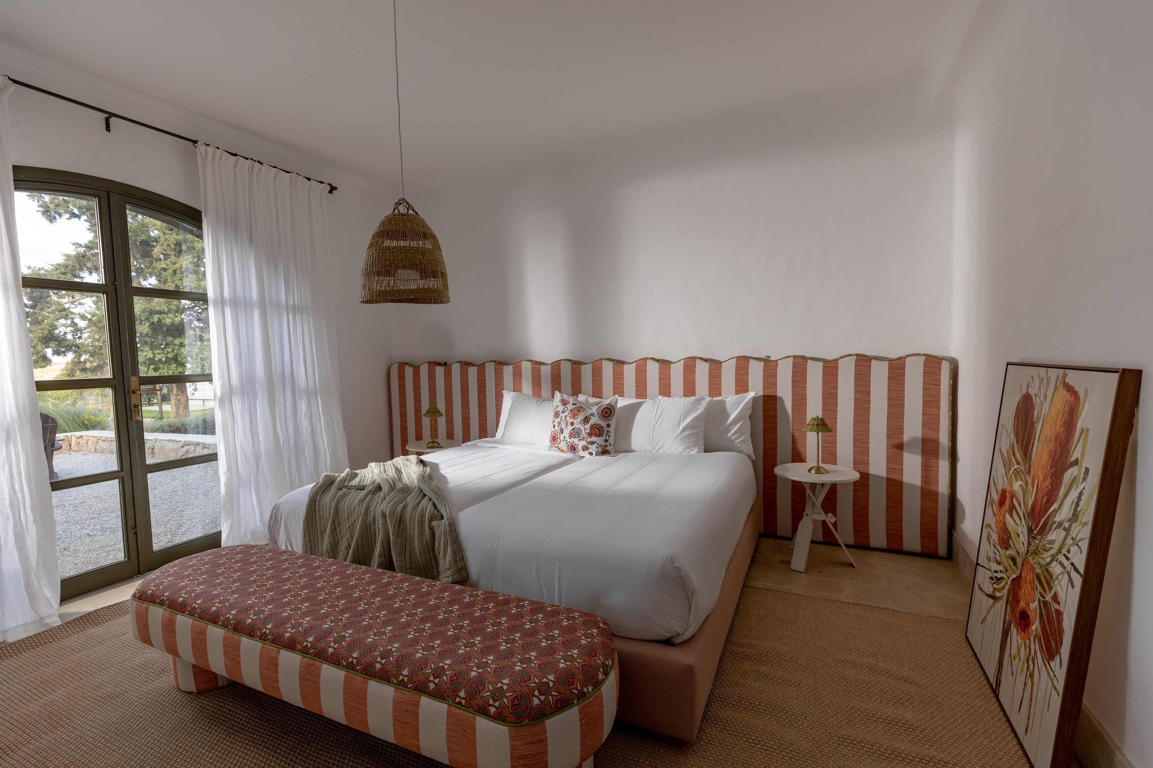 Chambre double à la grande tête de lit ondulée rayée terracotta, voilages et osier