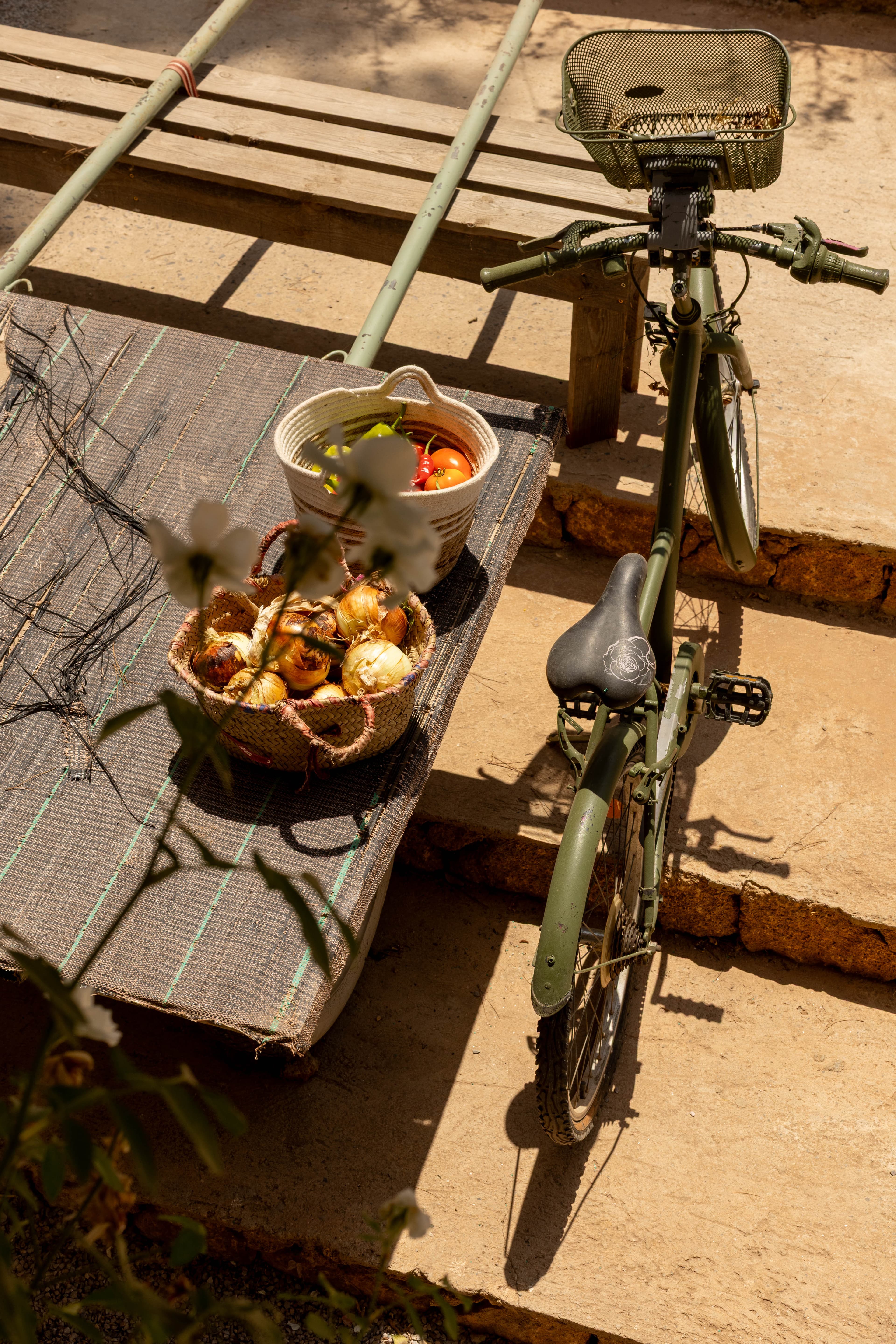 Vélo kaki appuyé près de paniers d'oignons et de tomates fraîchement récoltés au soleil