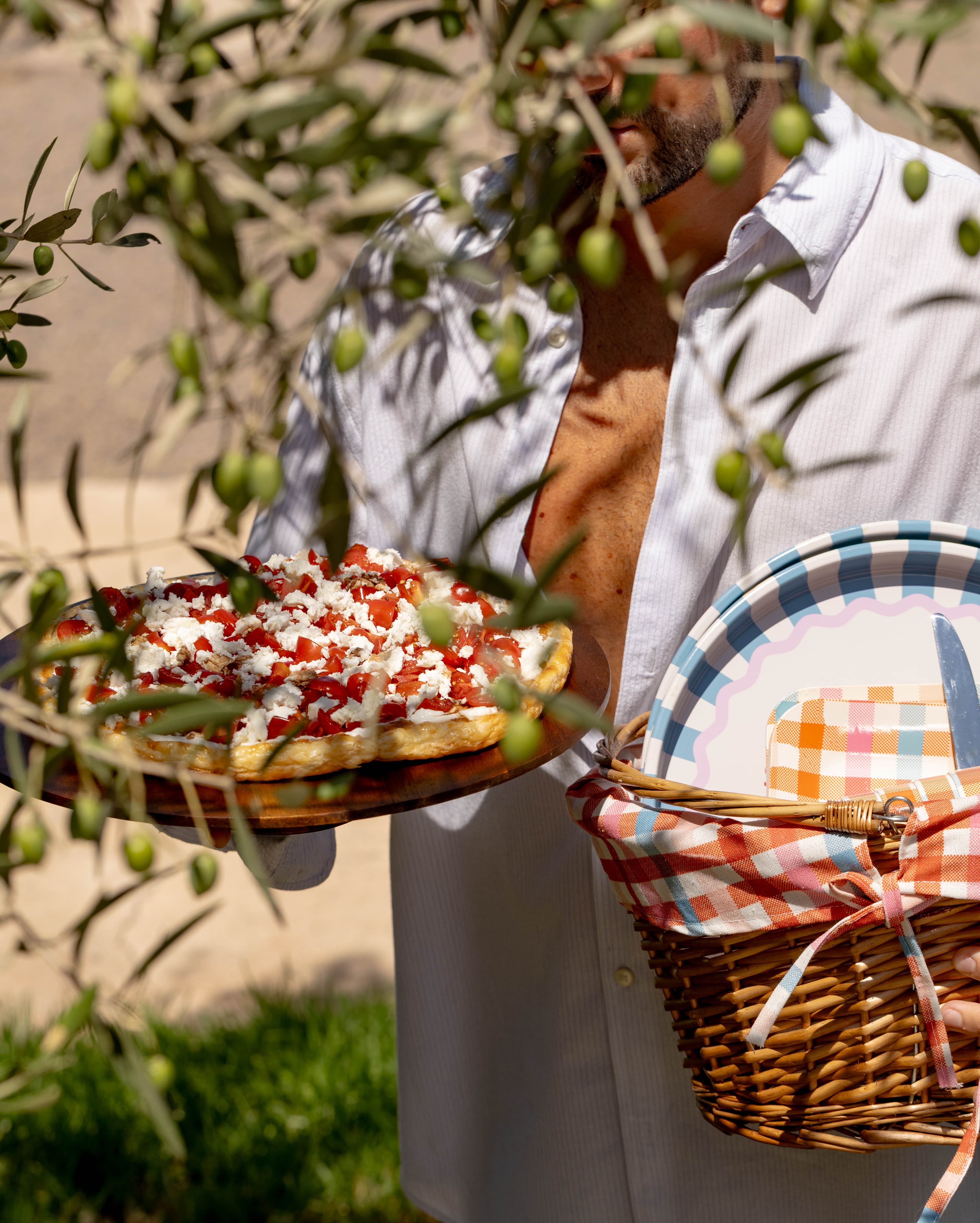 La tarte portée sur sa planche sous la branche d'olivier, panier au bras