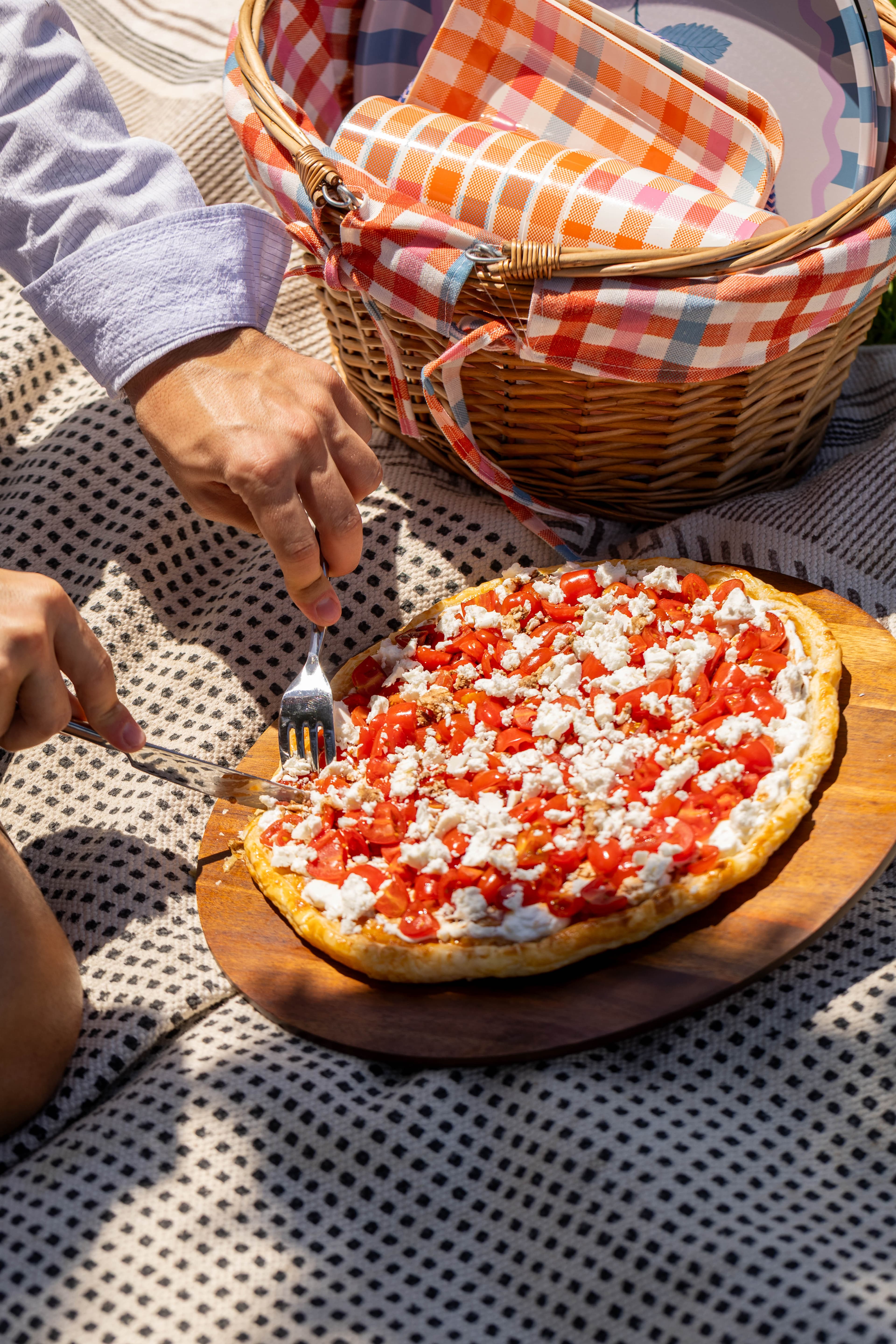 Fourchettes dans la tarte tomates et feta, panier et plaid sur l'herbe