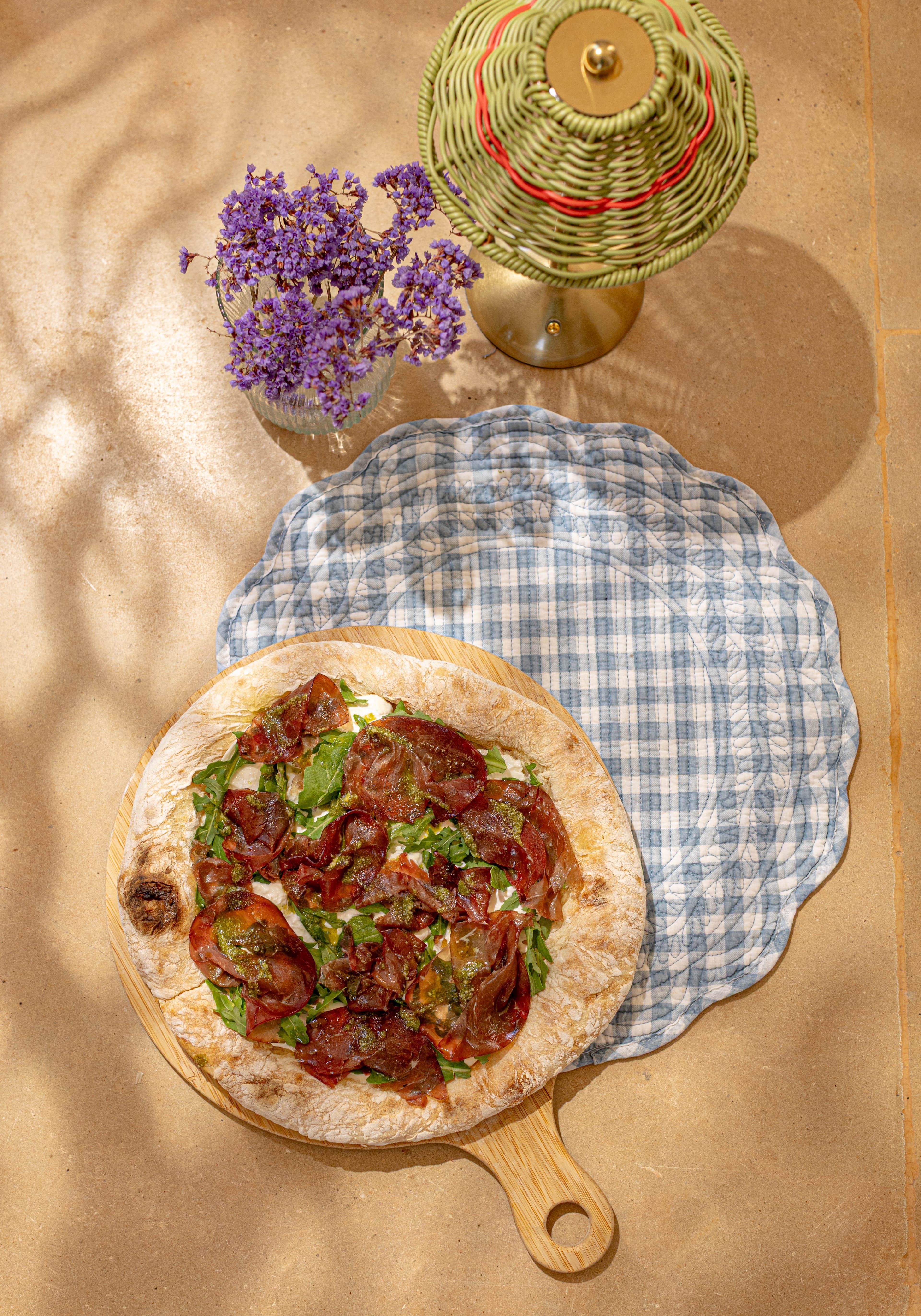 Pizza à la saucisse et à la roquette vue du ciel, sur la nappe vichy