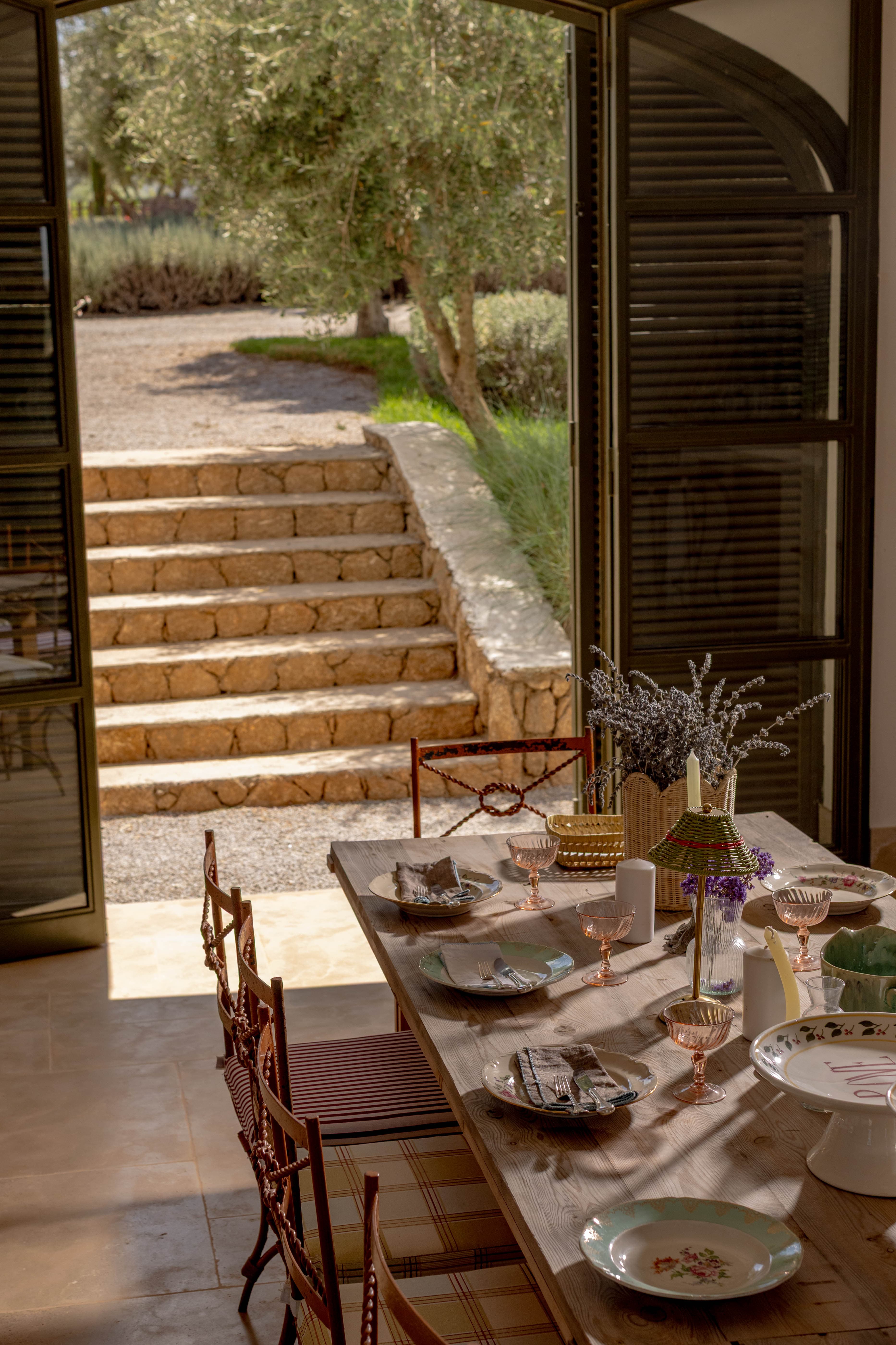 La table dressée près de la porte ouverte sur les marches du jardin et l'olivier